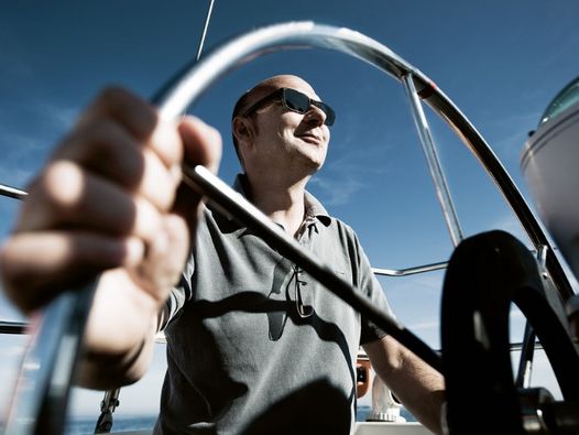 Prokurist Volker Reichelt am Steuer einer Segelyacht 