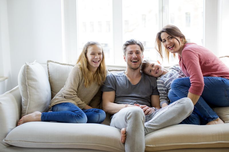 Glückliche Familie sitzt lachend auf dem Sofa