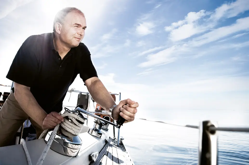 Geschäftsführer Andreas Medicus kurbelt an der Winsch einer Segelyacht – Kompetenz bei der Hamburger Yachtversicherung Schomacker